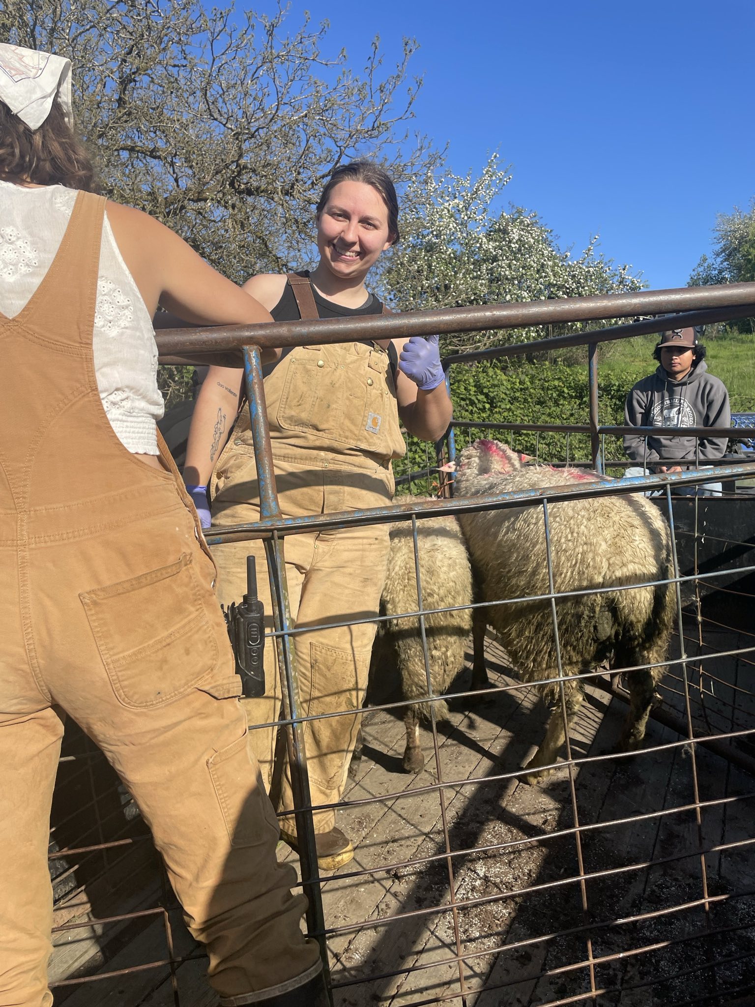 Farm worker smiling while doing foundation work in front of a rustic round building.