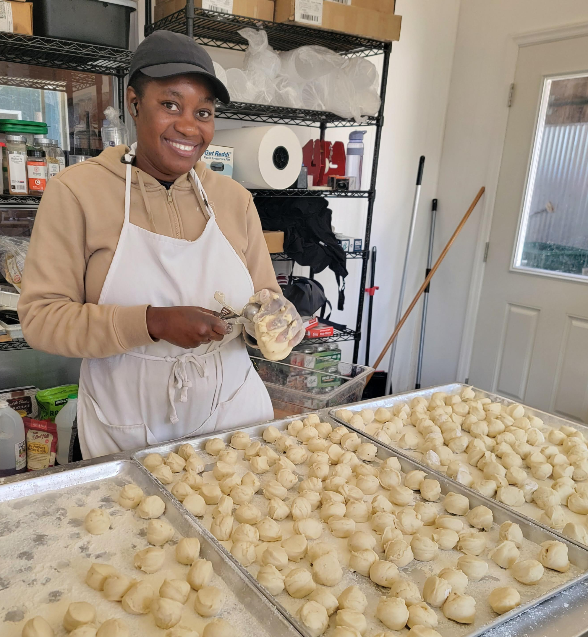 Farm worker shaping rounds of cheese on trays in a processing room.
